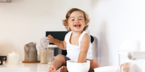Lachend kind in wit shirt op het keukenblad